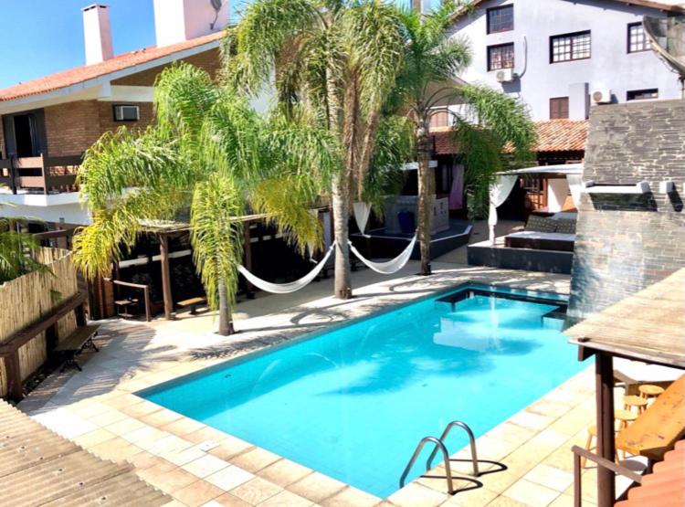 里奥格兰德Lira Hotel & Restaurante的大楼前带吊床的游泳池