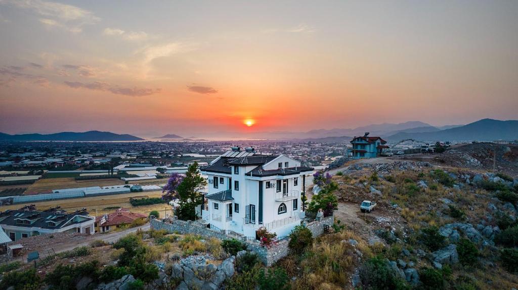 费特希耶Sessiz,Sakin, huzurlu jakuzi ve saunalı deniz,doğa manzaralı müstakil villa的山丘上的房子,背景是日落