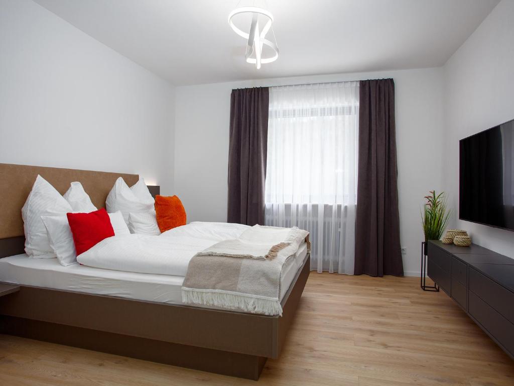 KammersteinZwick Apartments的一间卧室配有一张带红色枕头的床和电视。