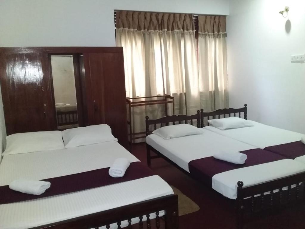 康提Lazy Bear Best Hostel in Kandy的一间卧室配有两张带白色枕头的床