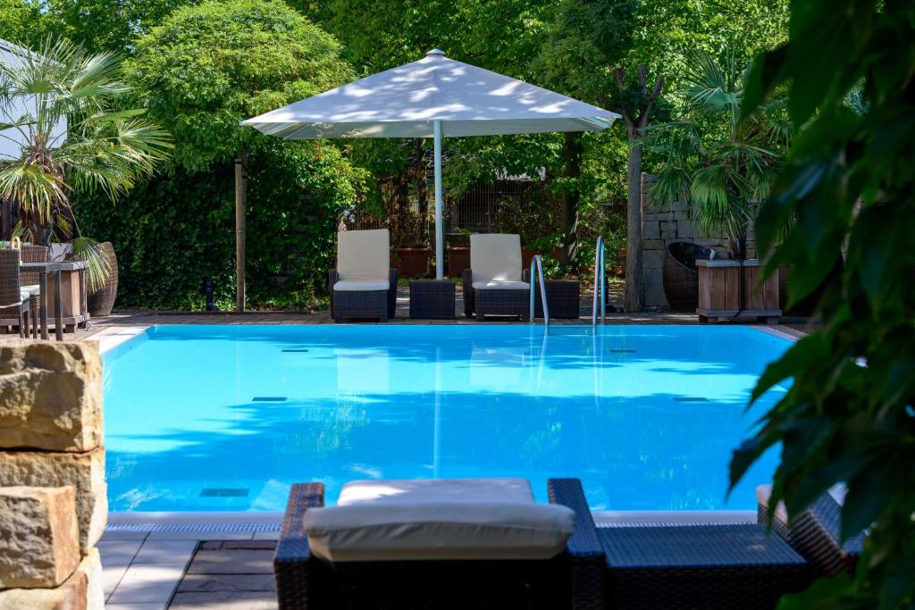 汉诺威汉诺威迈迪卡公园美居酒店的一个带遮阳伞和椅子的游泳池