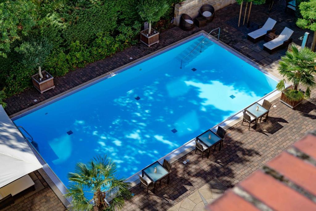 汉诺威汉诺威迈迪卡公园美居酒店的享有带椅子的大型蓝色游泳池的顶部景致