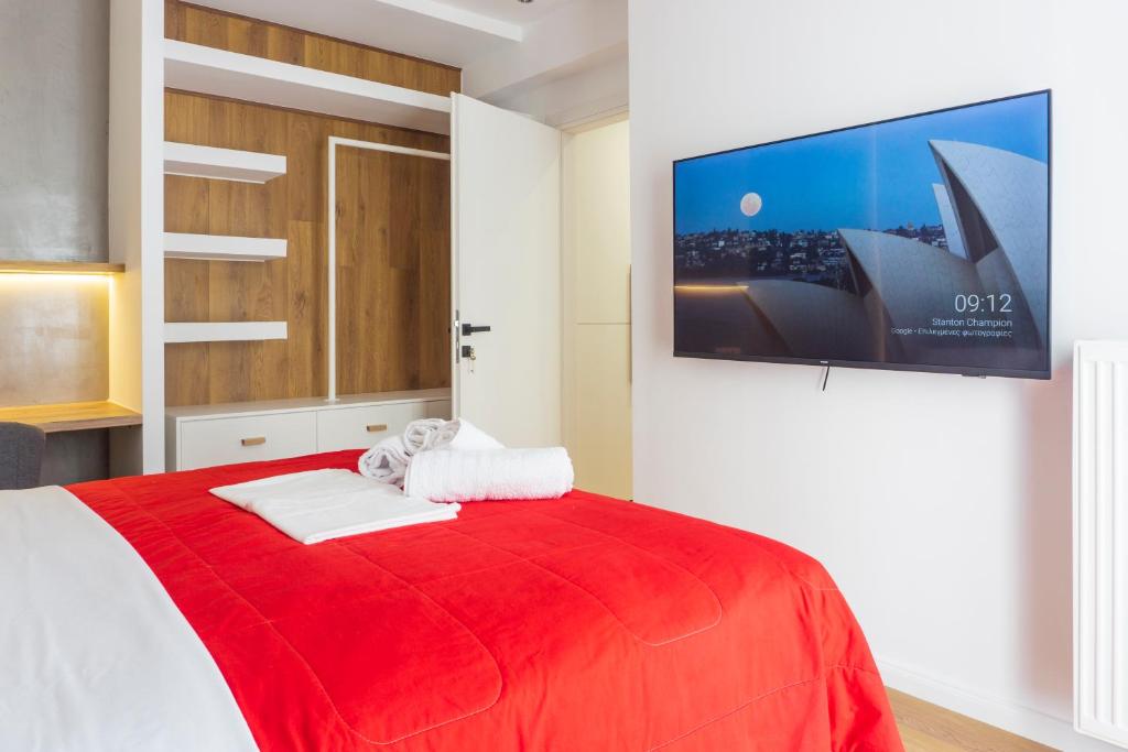 塞萨洛尼基New modern style home next to the train station的卧室配有红色的床和壁挂式平面电视。