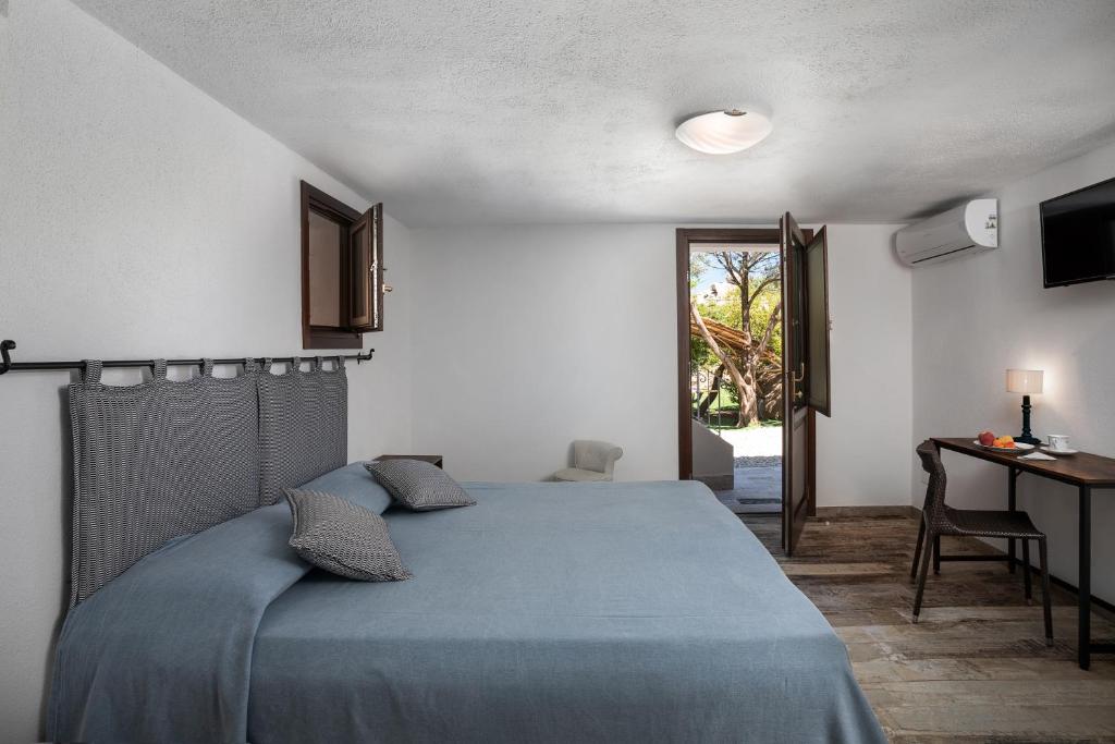 巴哈撒丁岛Il Mirto的一间卧室配有一张床、一张书桌和一个窗户。