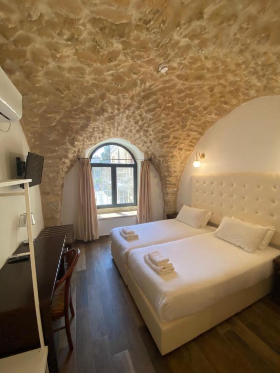 耶路撒冷Petrakis Inn的一间卧室设有两张床和石墙