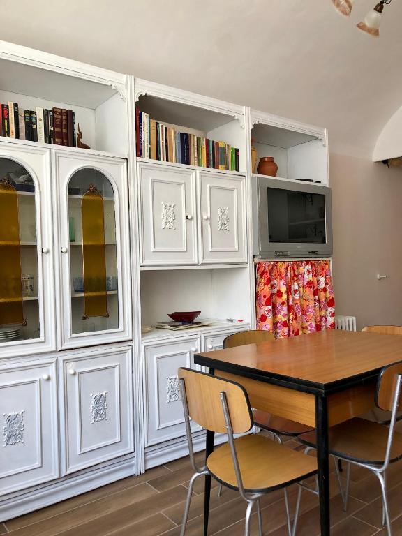 CandeloLa Taverna del Ricetto的一间设有白色橱柜和桌椅的用餐室