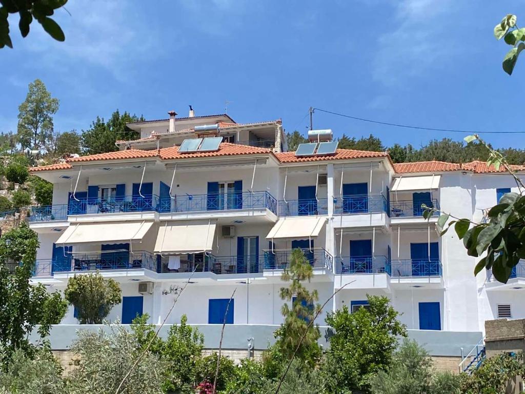 蒂洛斯Matina Apartments Tyros的白色的大公寓大楼设有蓝色的阳台
