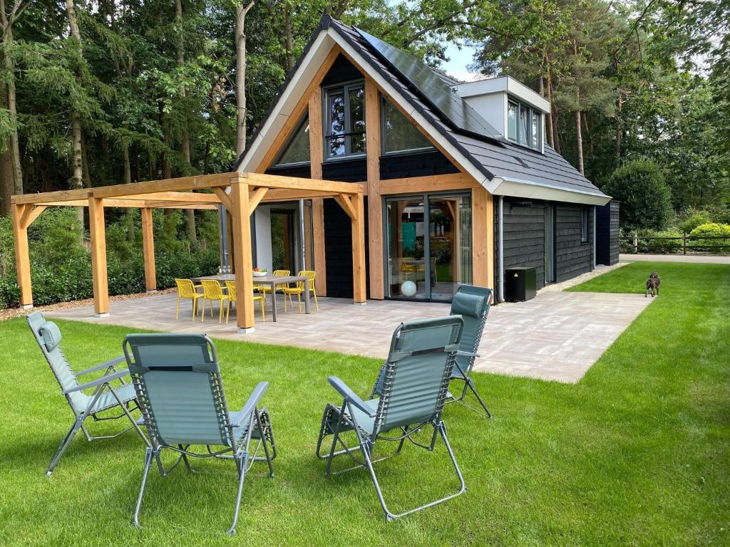 洛赫姆Modern holiday home in Lochem with private garden的坐在房子前面的草上,一群椅子