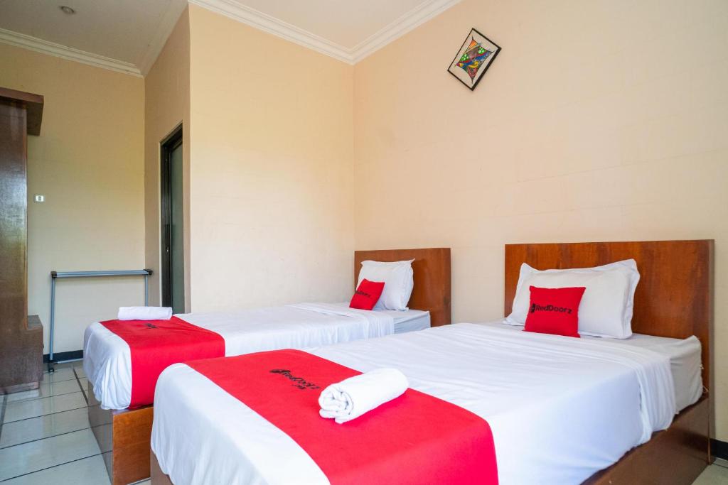BojonegoroRedDoorz Plus Syariah At Lotus Hotel Bojonegoro的配有红色和白色床单的客房内的两张床