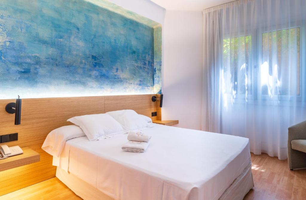 巴古尔Hotel Rosa & Spa Begur的卧室配有一张白色床,墙上挂有绘画作品