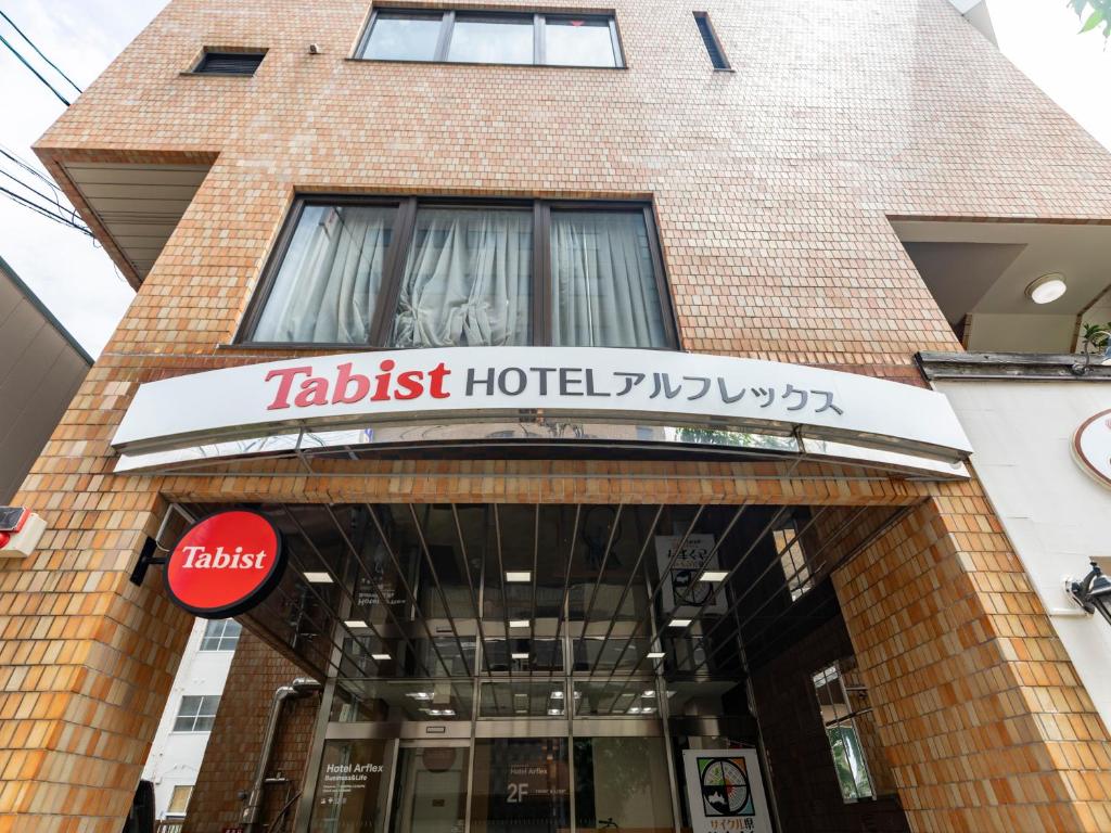 周南市Tabist HotelArflex Tokuyama Station的大楼前的酒店标志