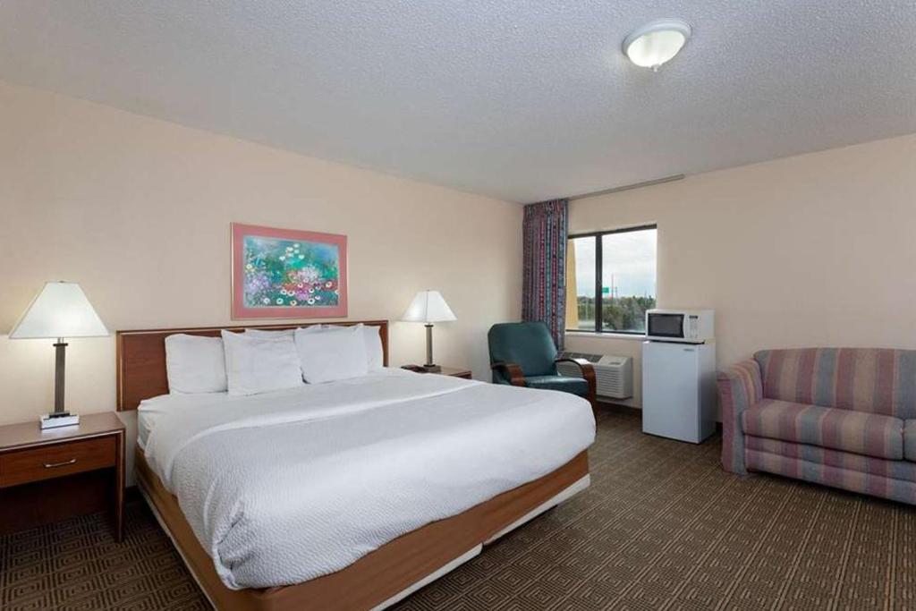 印第安纳波利斯Norwood Inn & Suites Indianapolis East Post Drive的酒店客房带一张大床和一把椅子