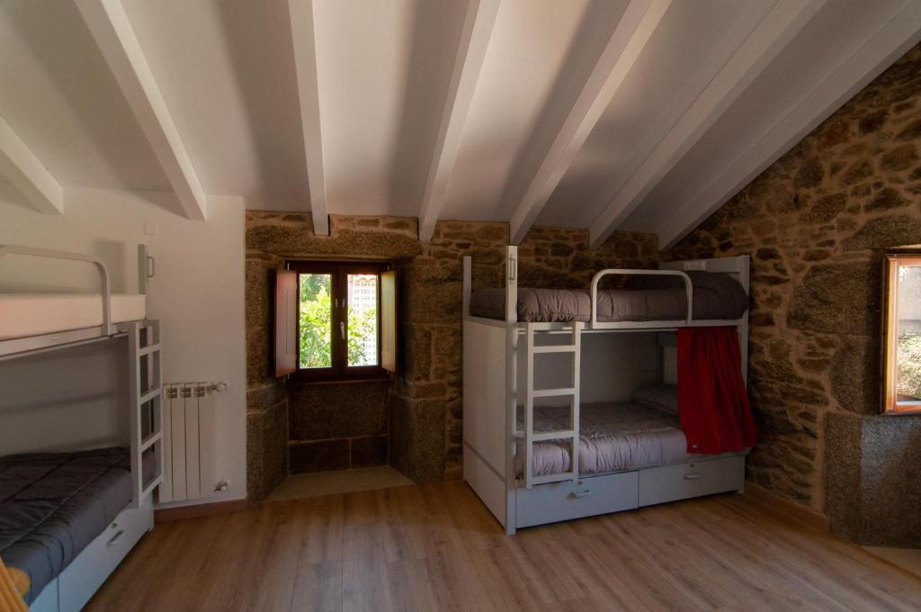 AmésA Casa Do Boi的石头建筑中带双层床的房间