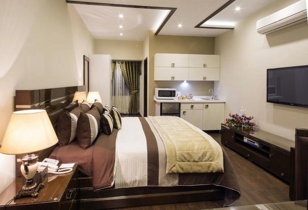 拉合尔Royaute Luxury Suites and Hotel Gulberg Lahore的一间带大床的卧室和一间厨房