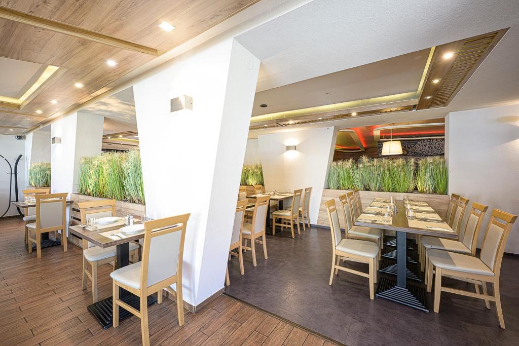 考普堡Jam Panzió的餐厅设有木桌和椅子,种有植物