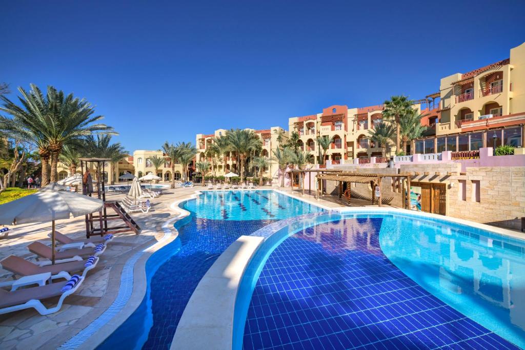 亚喀巴Marina Plaza Hotel Tala Bay的棕榈树和建筑度假村的游泳池