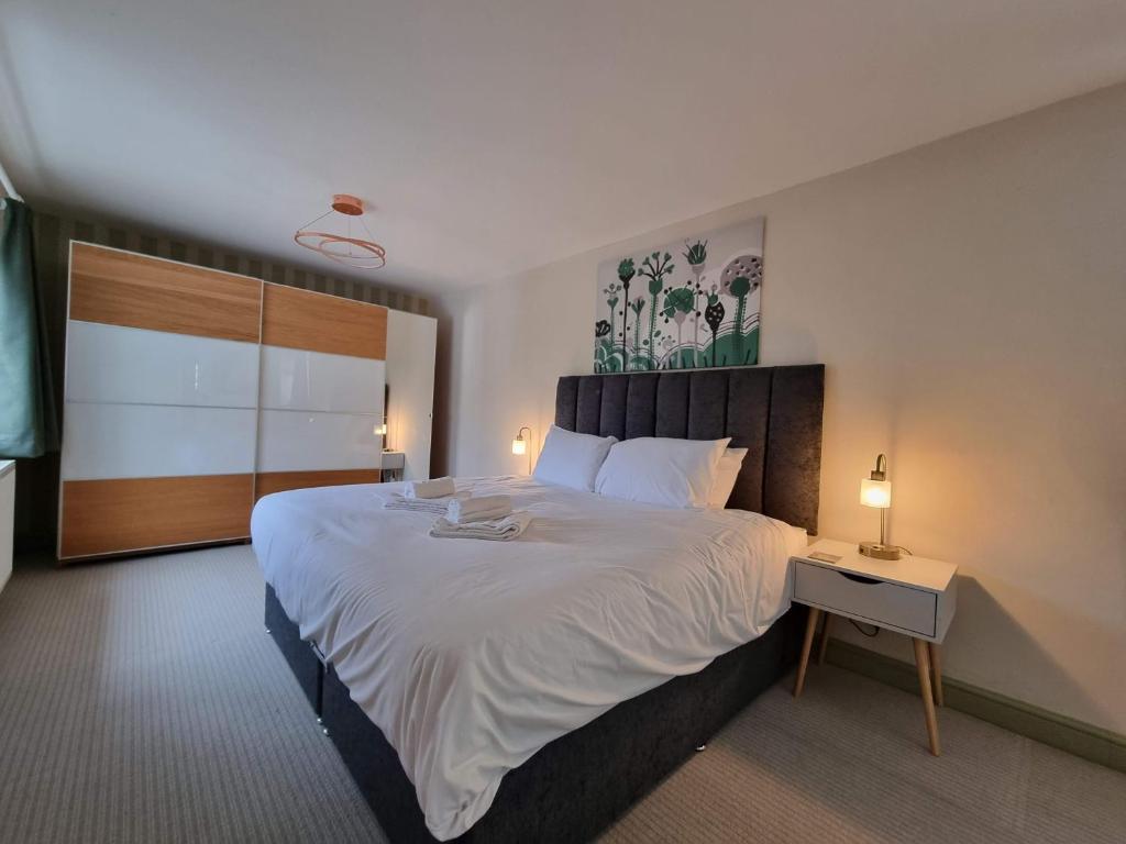 布里斯托Kingsfield House by Cliftonvalley Apartments的卧室配有一张白色的大床和床头柜。