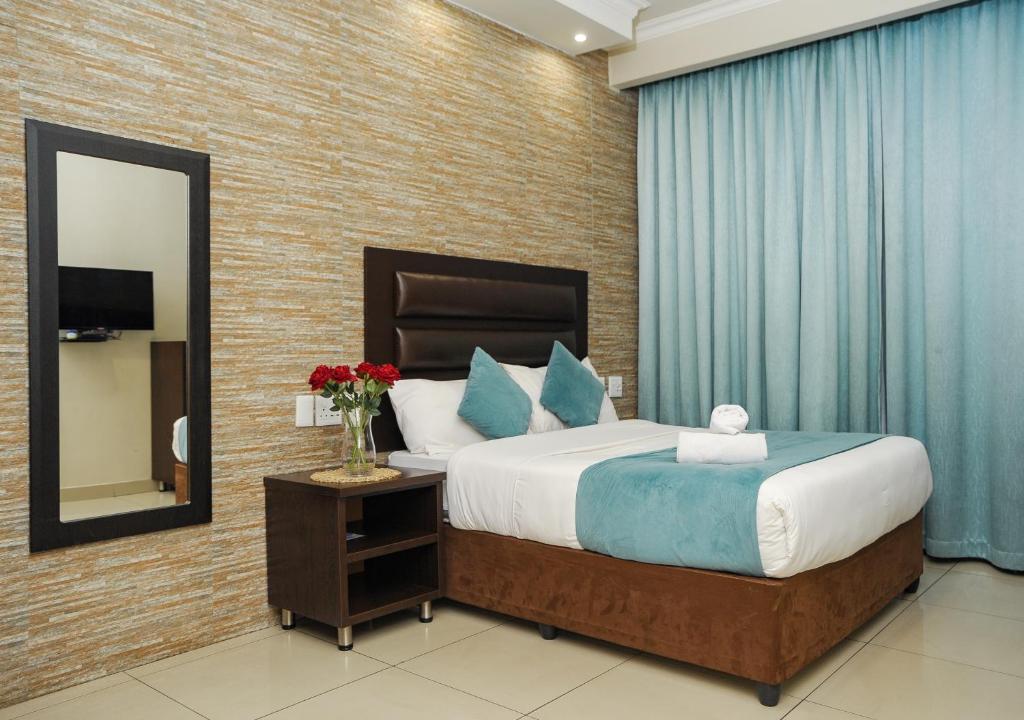 彼得马里茨堡Bayside Hotel Pietermaritzburg的一间卧室配有一张大床和镜子