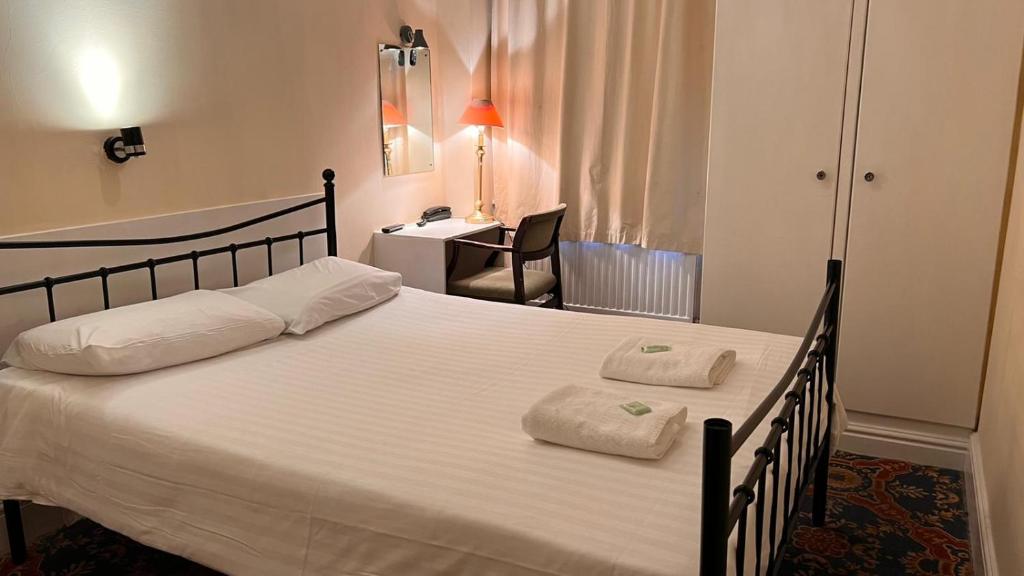 伦敦布鲁姆斯伯里格雷西姆酒店的一间卧室配有一张大床和两条毛巾
