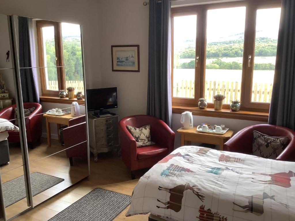 因弗内斯Doura Lodge的一间卧室配有一张床、椅子和窗户。