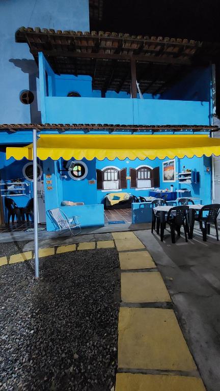阿拉亚尔-杜卡布PARAÍSO TOM DO MAR 2的蓝色的建筑,设有黄色遮阳篷和桌椅