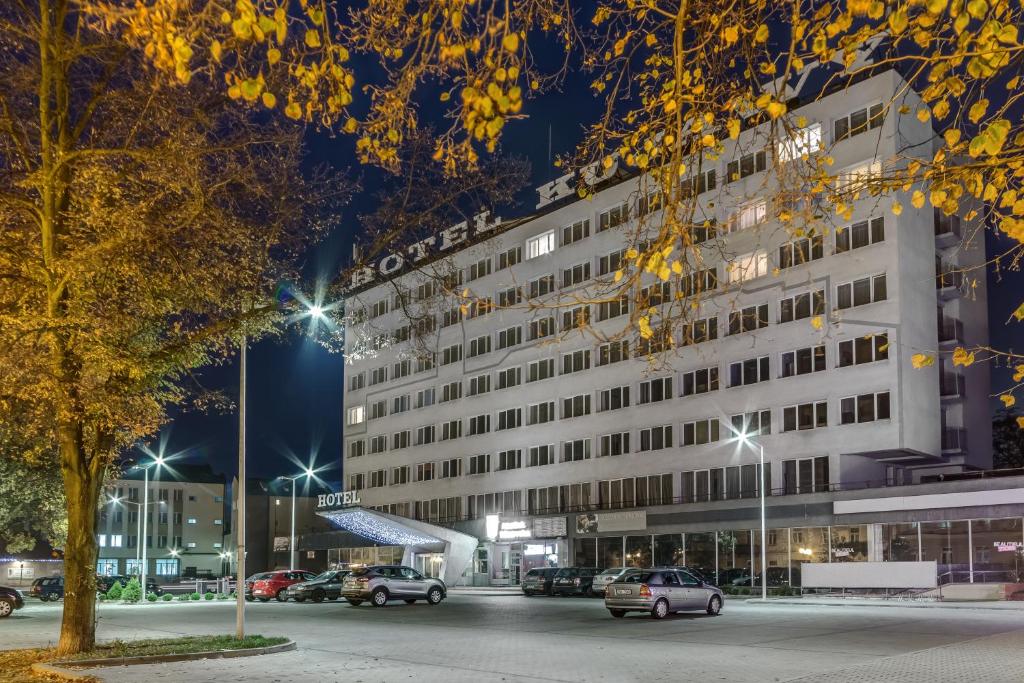 弗沃茨瓦韦克Hotel Kujawy的一座白色的大建筑,汽车停在停车场