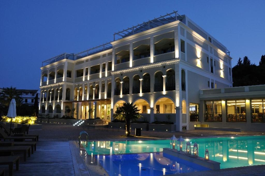 科孚镇Corfu Mare Hotel -Adults only的一座白色的大建筑,前面设有一个游泳池