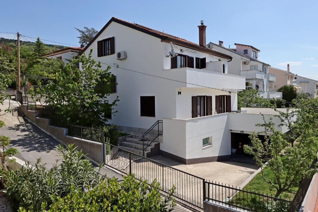 塞尔瑟Apartments and rooms with parking space Selce, Crikvenica - 2362的白色的房子,有黑色的栅栏和树木