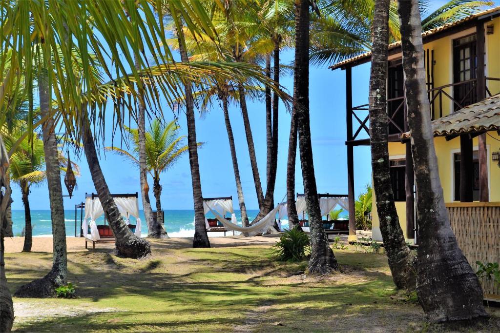 巴拉格兰德Rumah Pousada的海滩上种有棕榈树和吊床的度假胜地