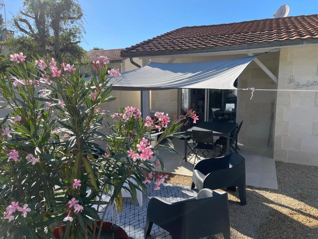 滨海沃Calme et ensoleillée Maison au pied de la plage entre St Palais sur Mer et Royan的庭院配有桌椅和粉红色的鲜花。