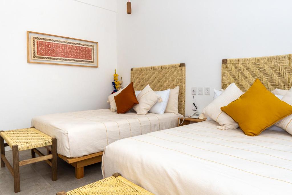 瓦哈卡市Santa Cecilia Hotel的酒店客房,配有两张床和椅子