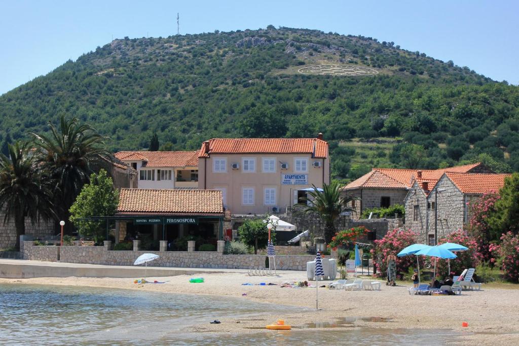 斯拉诺Apartments and rooms by the sea Slano, Dubrovnik - 2687的一座拥有建筑的海滩和一座山的背景
