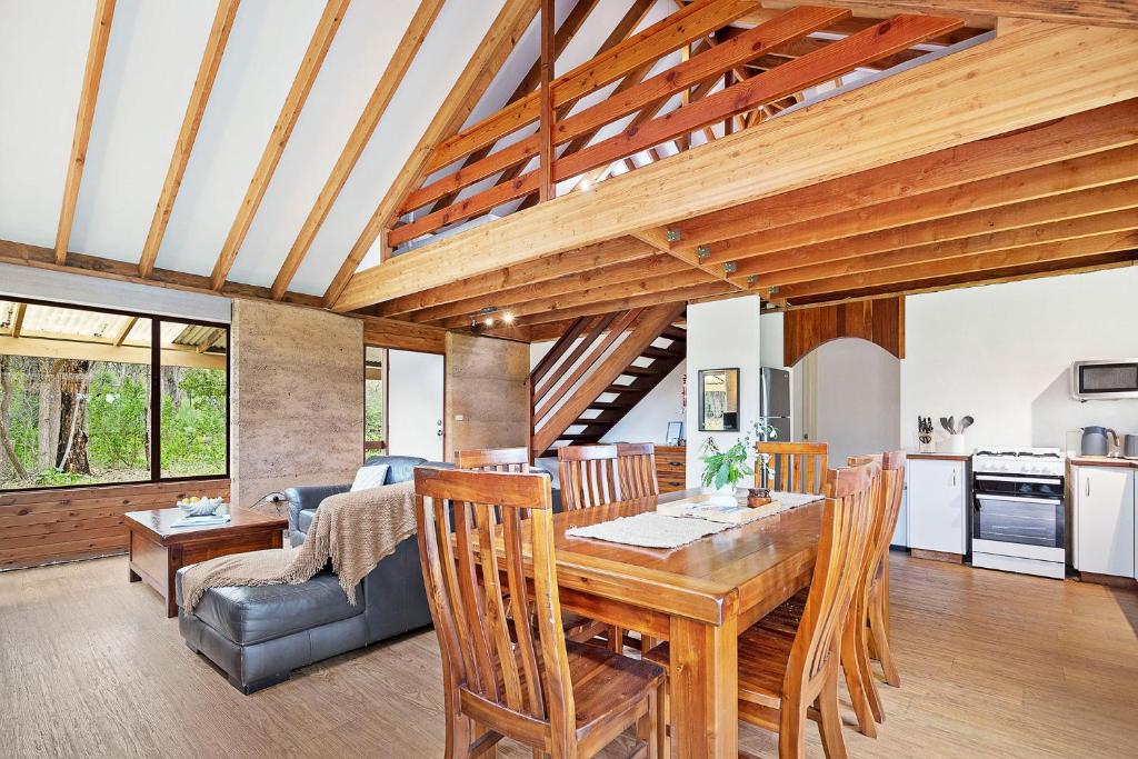 邓斯伯勒Kookaburra Cottage at Woodstone Estate的厨房以及带木桌和椅子的客厅。
