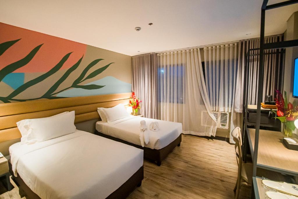 麦克坦1521 Hotel & Spa的酒店客房设有两张床,墙上挂有绘画作品