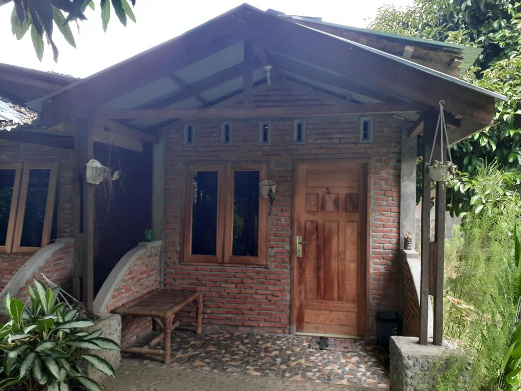 武吉拉旺Jhony's Backpacker-Guest House的砖屋,木门和长凳