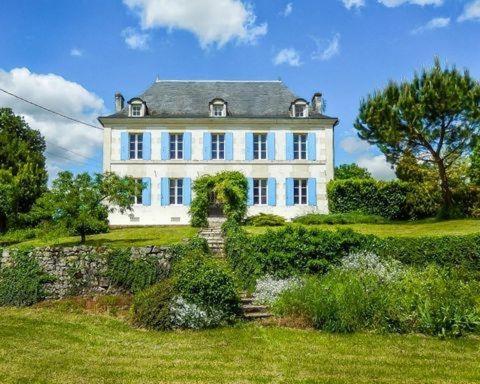 Saint-PorchaireVilla Mamba的一座大型白色房子,位于郁郁葱葱的绿色田野上