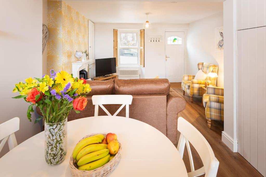托基*Brand New* Olive Grove Cottage的客厅里设有一张桌子,上面放着香蕉和鲜花