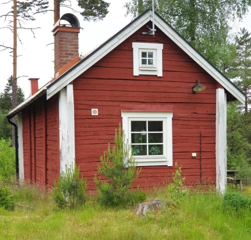 BodaforsCabin near lake and beautiful nature reserve.的一间红色的房子,有白色的窗户和烟 ⁇ 
