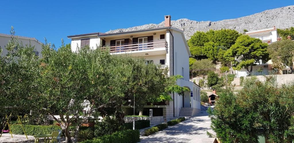 杜埃Apartments by the sea Duce, Omis - 2821的山前有树木的白色建筑