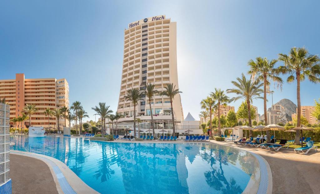 卡尔佩Hotel RH Ifach的一座棕榈树和建筑的大型游泳池