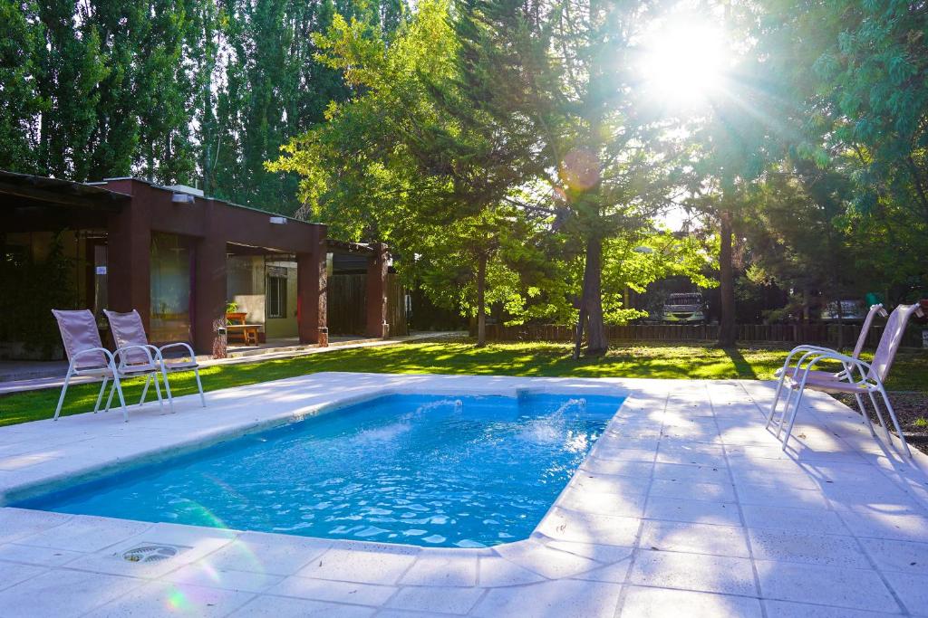 卢汉德库约Cabañas Parque Vistalba的庭院中带椅子和阳光的游泳池