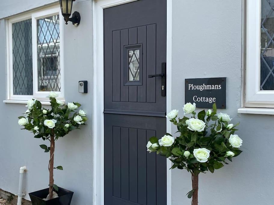 滕比Ploughmans Cottage, St Florence, Tenby的房子前面有鲜花的黑色门