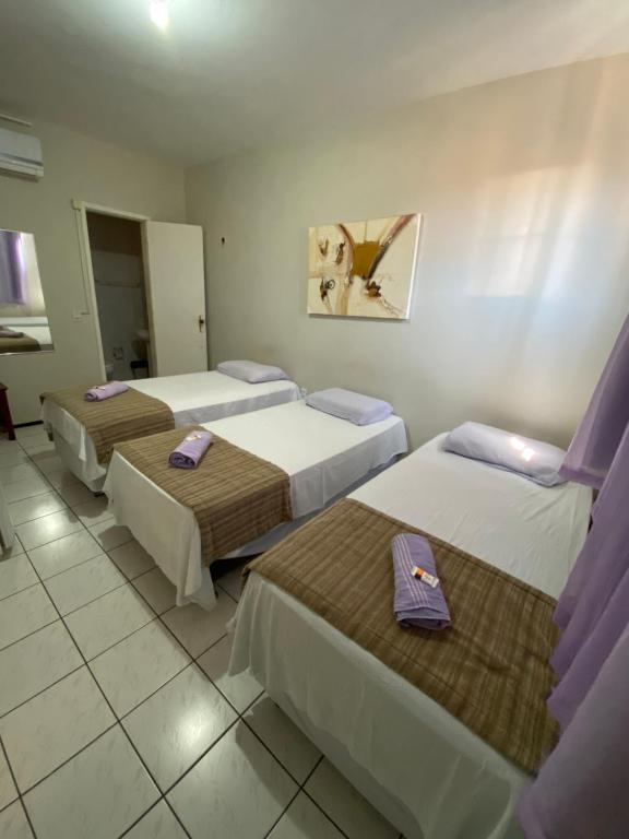 福塔莱萨Center 1 Hotel的酒店客房,配有三张床,上面有紫色的餐巾