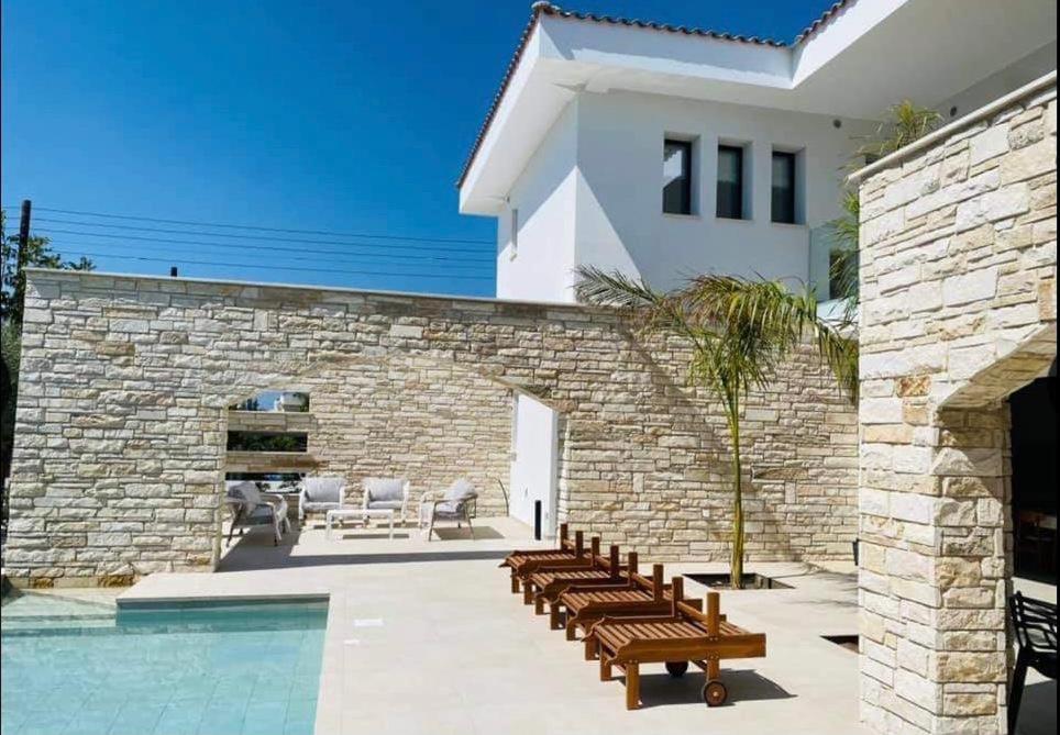 帕福斯Paphos luxury contemporary villa的一座房子,设有游泳池,毗邻石墙