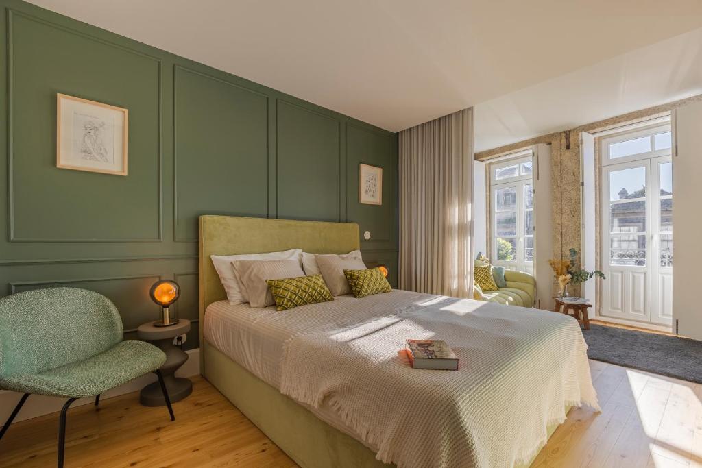 波尔图As Vizinhas Boutique Apartments的绿色卧室配有床和椅子