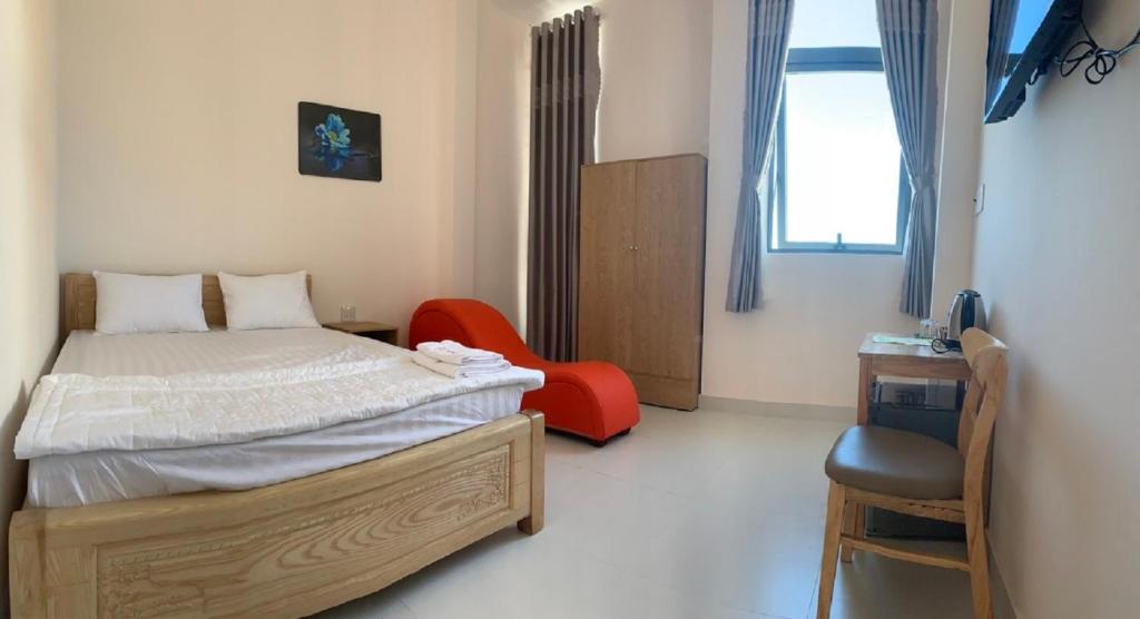 Bạc LiêuKhách Sạn HOÀNG KIM的一间卧室配有一张床和一张红色椅子