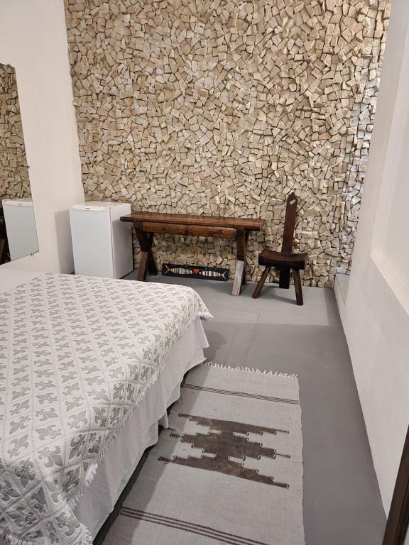 皮帕Buddha Suítes的一间卧室设有一张床、一张长凳和石墙