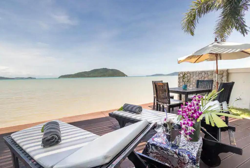 拉威海滩拉亚海滨度假屋的一个带椅子和遮阳伞的甲板和水