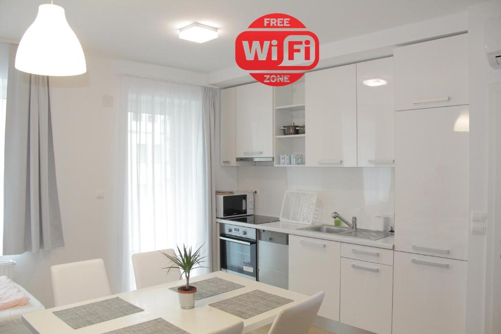 维也纳贝塔里尔S22号公寓的厨房配有白色橱柜和桌椅