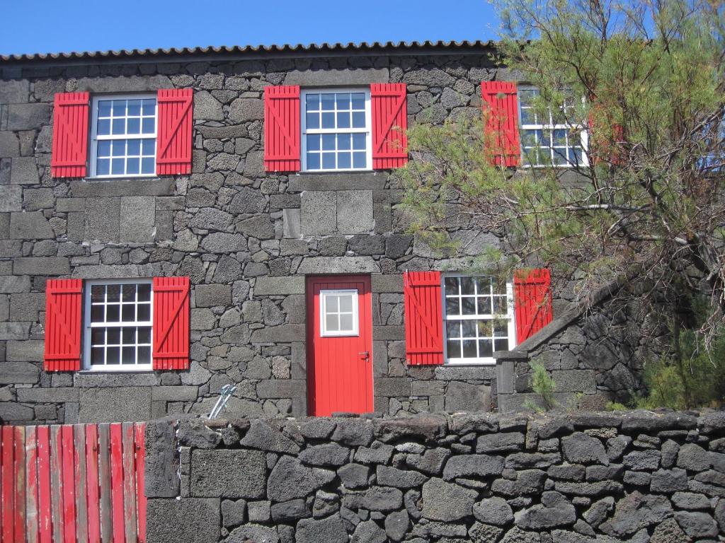 ArcosCasa do Jardim de Lava的一座石头建筑,设有红色的窗户和红色的门